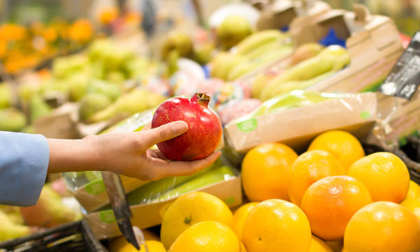 istock Women hand choosing pomegranate at supermarket 1144320236