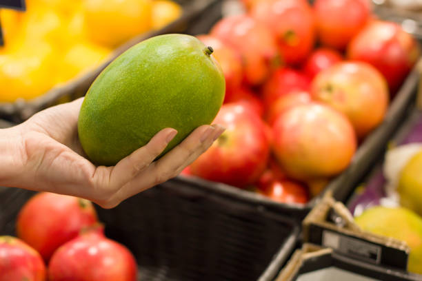 frauen wählen mango im supermarkt - refrigerator healthy eating mango fruit stock-fotos und bilder