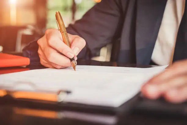 Photo of Close up business man reaching out sheet with contract agreement proposing to sign.Full and accurate details, individual who owns the business sign personally,director of the company, solicitor.