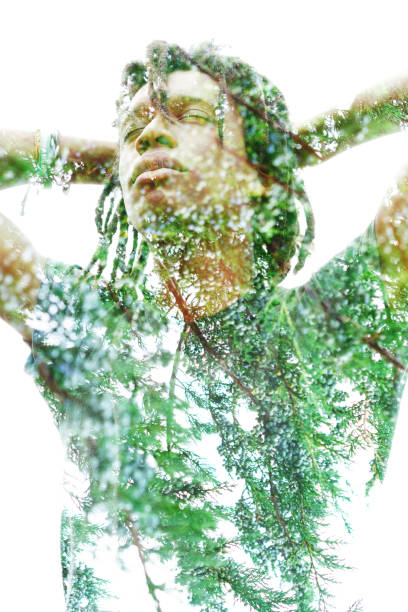 istock Double exposure of a dark skinned man with dreadlocks and hands behind head combined with a photograph of green leafy tree branches 1144330479