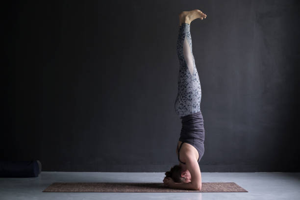woman practicing yoga, doing headstand exercise, salamba sirsasana pose Young sporty woman practicing yoga, doing headstand exercise, salamba sirsasana pose, working out shirshasana stock pictures, royalty-free photos & images