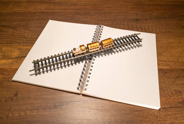 Golden wooden train on track on blank white notebook stock photo