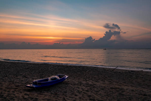 Sunrise in the morning with one boat on beach and one boat in the sea stock photo