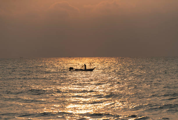 One fisherman on his boat with flash light of Sunrise stock photo