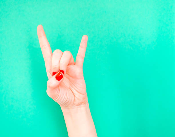 Woman hand shows Rock N Roll Hand Signs isolated on turquoise green color background. Sign of the horns. If you re feeling super cool, do the rock n roll hand sign Woman hand shows Rock N Roll Hand Signs isolated on turquoise green color background. Sign of the horns. If you re feeling super cool, do the rock n roll hand sign. rocker nails stock pictures, royalty-free photos & images