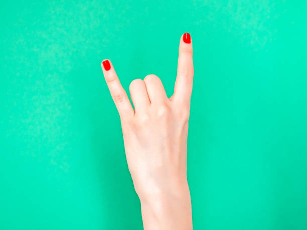 Woman hand shows Rock N Roll Hand Signs isolated on turquoise green color background. Sign of the horns. If you re feeling super cool, do the rock n roll hand sign Woman hand shows Rock N Roll Hand Signs isolated on turquoise green color background. Sign of the horns. If you re feeling super cool, do the rock n roll hand sign. rocker nails stock pictures, royalty-free photos & images