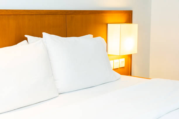 istock White comfortable pillow on bed with light lamp decoration in bedroom 1144338723