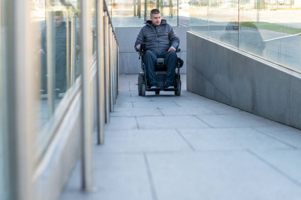 el hombre en una silla de ruedas eléctrica usando una rampa - cuadriplégico fotografías e imágenes de stock