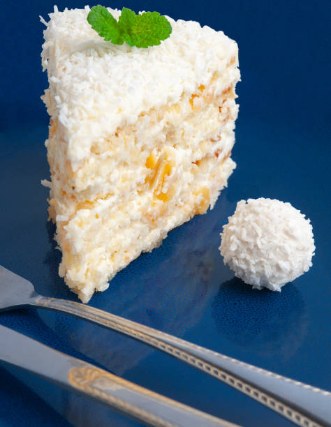 istock A piece of white cake with almonds and coconut chips on a blue plate. Decorated with mint and candy with coconut 1144347776