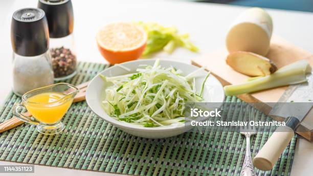 Dietary Vegetarian Salad Made From Daikon Radish Celery Cucumber And Spring Onions In A Plate And With Ingredients On The Table An Organic Dish Stock Photo - Download Image Now