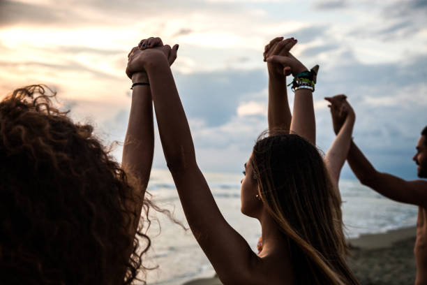 group of friends on the beach holding and raising hands all together - group of people women beach community imagens e fotografias de stock