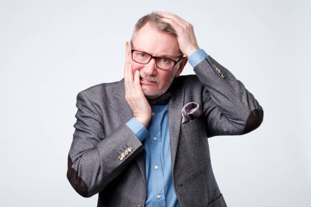 istock man holding hand on his head having forgetful look 1144355298