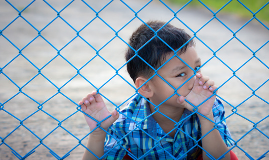 The boy behind the net with a depressed face.