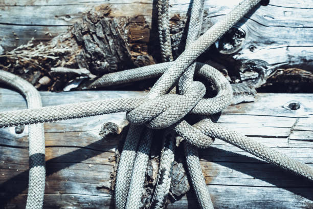 A weathered hemp cord is wrapped around a wooden post. Moss has already settled on the string. There is space for text