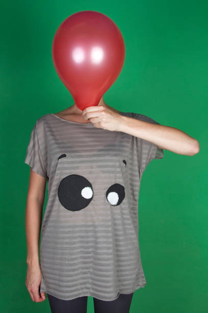 istock Women posing with their faces covered with balloons green screen - Image 1144359497