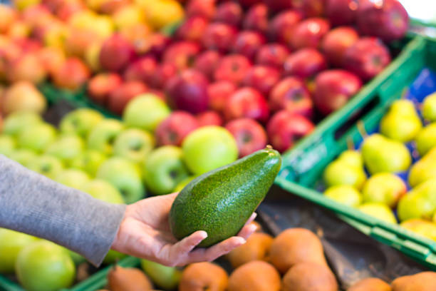istock Women hand choosing avocado at supermarket 1144361452