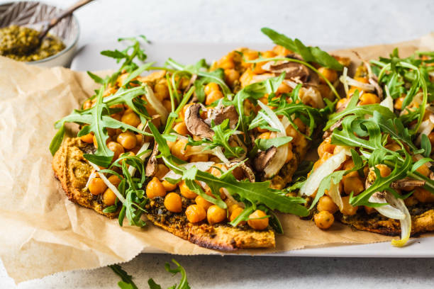 Green vegan pizza with pesto, chickpeas, champignons and arugula.