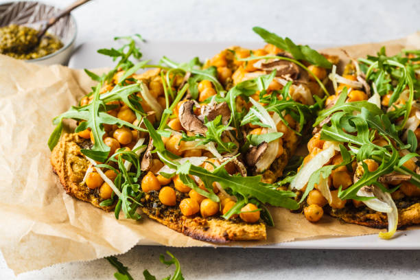 Green vegan pizza with pesto, chickpeas, champignons and arugula. Green vegan pizza with pesto, chickpeas, champignons and arugula. Plant based diet concept. tortilla flatbread stock pictures, royalty-free photos & images