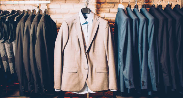 men formal wear classy outfit business suit Men formal wear. Classy outfit. Modern clothing store. Business suit jackets and vests hanging, displayed over brick wall. mens fashion stock pictures, royalty-free photos & images