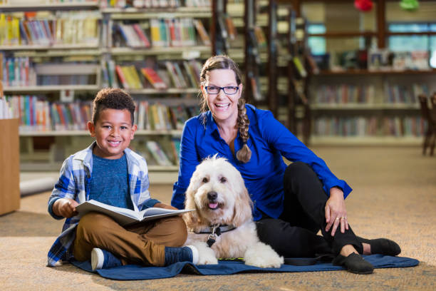 istock Mixed race boy reading in library with therapy dog 1144371943