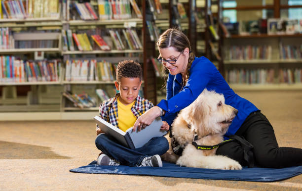 istock Mixed race boy reading in library with therapy dog 1144372191