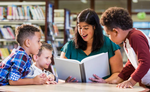 istock Hispanic teacher with three boys in library reading book 1144374023