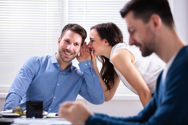 istock Two Businesspeople Gossiping About Their Colleague 1144374077