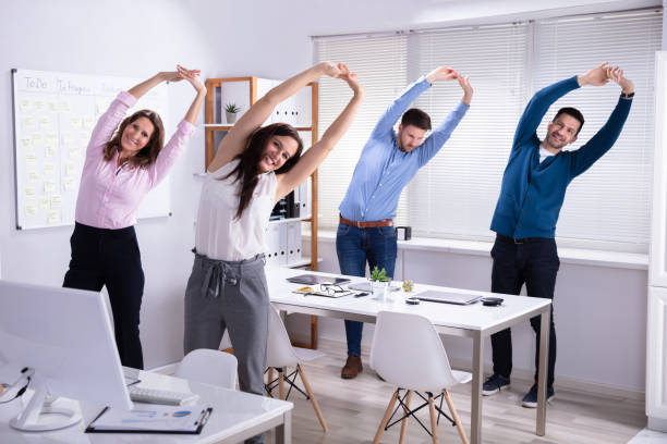 Businesspeople Doing Exercise Behind Desk Happy Businesspeople Doing Stretching Exercise Behind Desk At Workplace office competition stock pictures, royalty-free photos & images