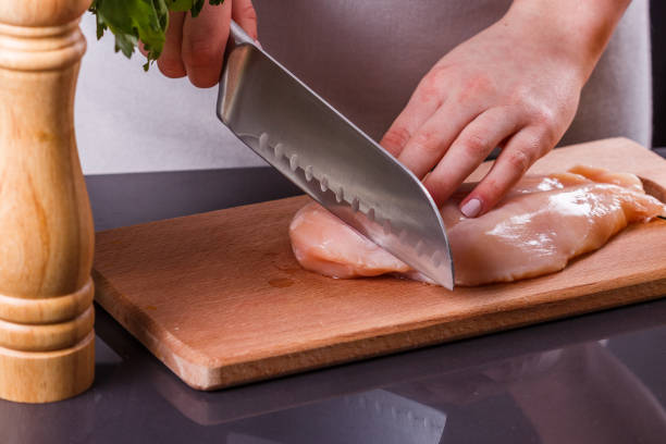 istock young woman in a gray apron cuts chicken breast 1144378574