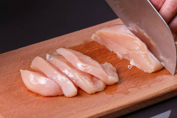 istock young woman in a gray apron cuts chicken breast 1144378578