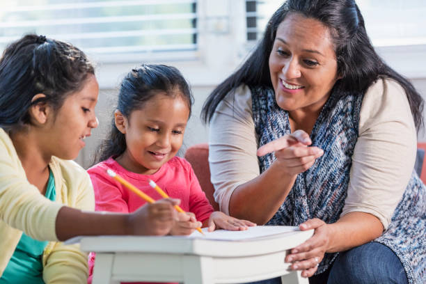 istock Hispanic mother helping girls with homework 1144381335