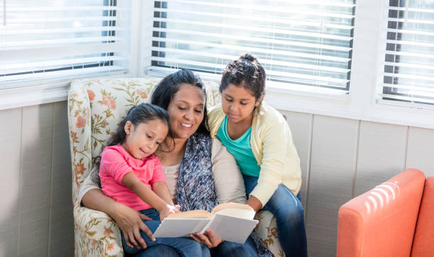 istock Hispanic mother reading to her two daughters 1144381544
