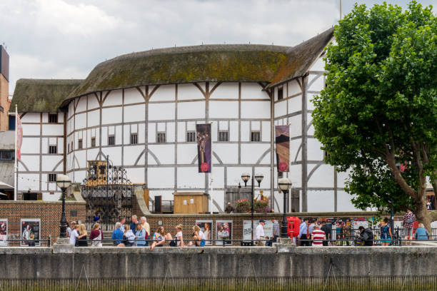 People walking on the Thames River coast sideway next to the Shakespeare Theatre, know as \