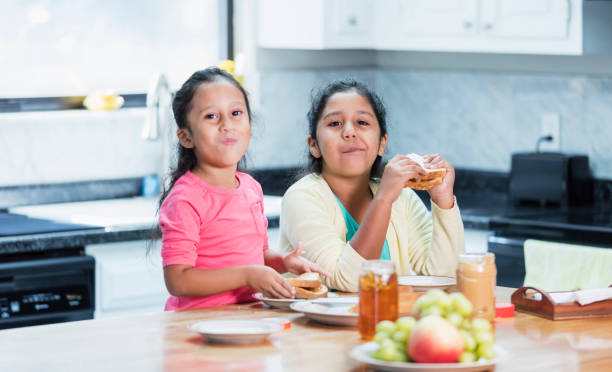istock Two Hispanic sisters eating peanut butter sandwiches 1144382324