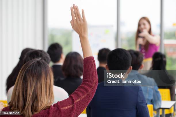 Young Businesswoman Raising Hand To Question From Speaker In Seminar Group Meeting Conference Concept Rear Back View Stock Photo - Download Image Now