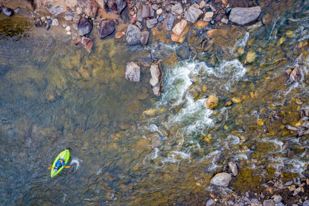Rear view of senior man paddling alone, wearing a safety jacket