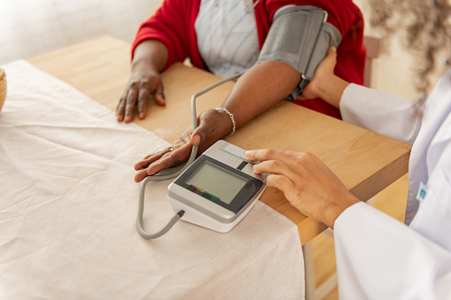 Checking blood pressure. Close up of professional nurse checking blood pressure for woman feeling unwell