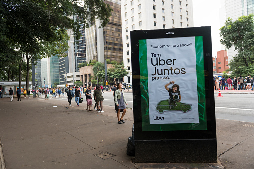 São Paulo, Brazil - April 14, 2019: An advertisement adjacent to a bus stop on Avenida Paulista promotes Uber Juntos, an option on Uber where you can get an even cheaper fare by sharing your ride with another user.