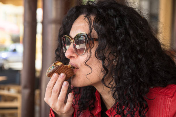 istock Young woman eating muffin cake 1144385973