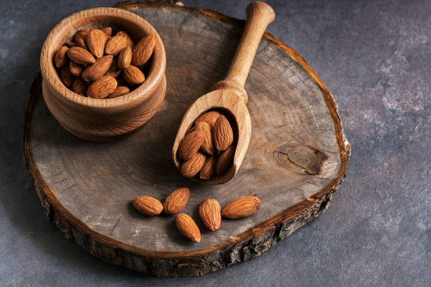 istock Almonds in a wooden scoop and a bowl on a stump cutting board. Selective focus. 1144389175