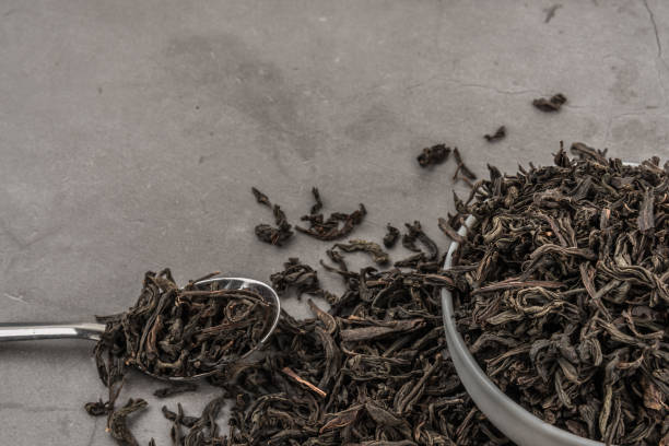 istock Dried tea in a white ceramic cup with a spoon on a gray textured background. 1144389321