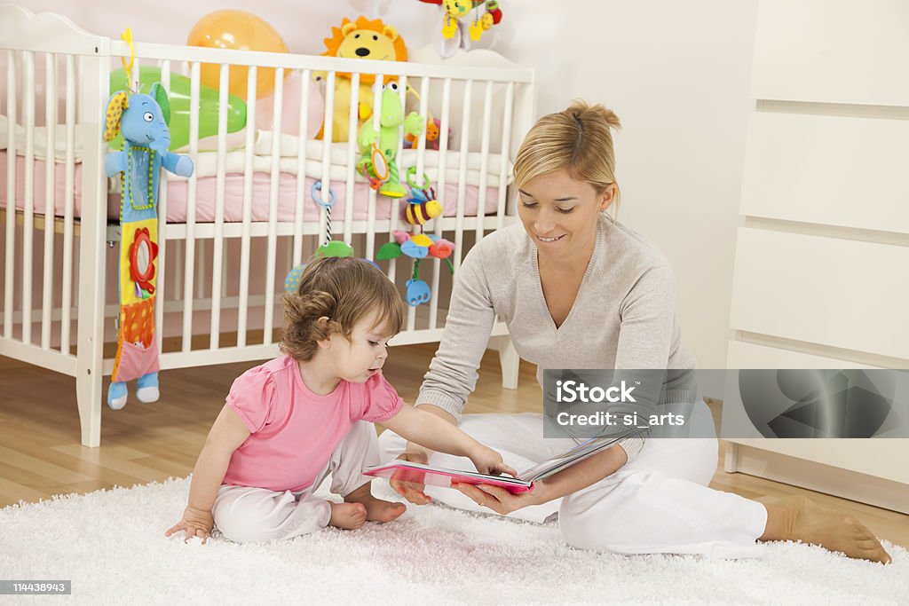 Mãe olhando para um livro com seu Bebé Menina - Royalty-free Bebé Foto de stock