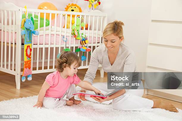 Mãe Olhando Para Um Livro Com Seu Bebé Menina - Fotografias de stock e mais imagens de Bebé - Bebé, Bebés Meninas, Criança