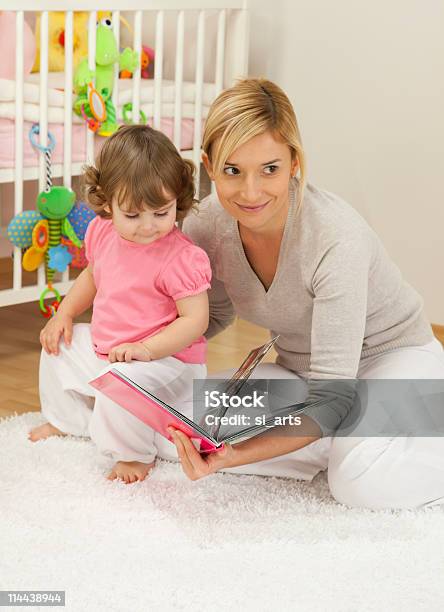 Madre Guardando Un Libro Con Suo Figlio Ragazza - Fotografie stock e altre immagini di Ambientazione interna - Ambientazione interna, Bambino, Bebé