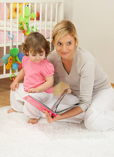 Mother Looking Book With Her Baby Girl stock photo