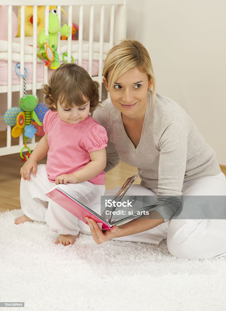 Мать Смотреть книгу с ее девочка-младенец - Стоковые фото Близость роялти-фри
