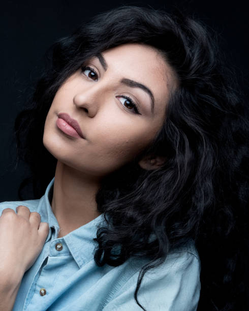 istock Good looking female with curly hair on black background 1144391323