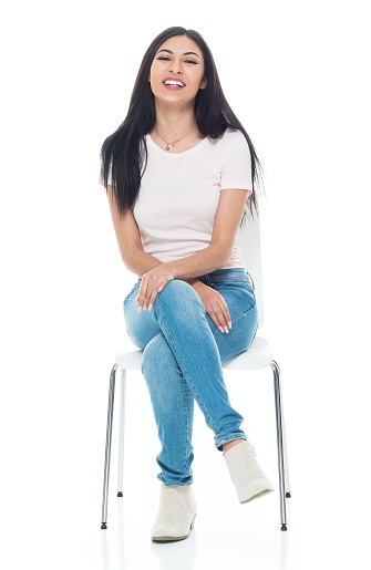 Beautiful young latino female wearing a tshirt and jeans - sitting