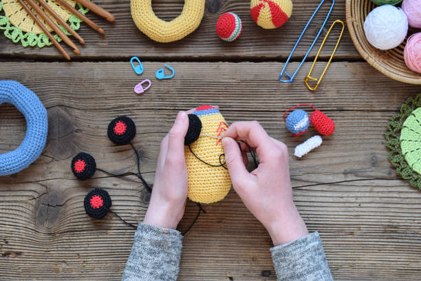 herstellung von farbigen häkel-rennwagen. spielzeug für babys und kleinkinder, um mechanische fähigkeiten und farben zu erlernen. auf den tischfäden, nadeln, haken, baumwollgarn. handwerk. diy-konzept. - cotton ball blue cotton crochet stock-fotos und bilder