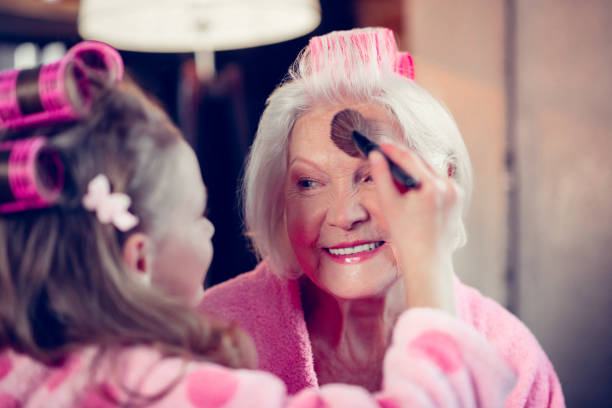 istock Girl doing makeup for her granny putting some face powder on 1144396417